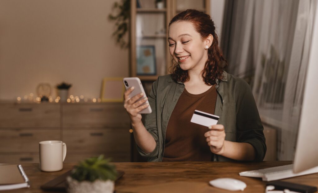 woman holding a credit card and a phone